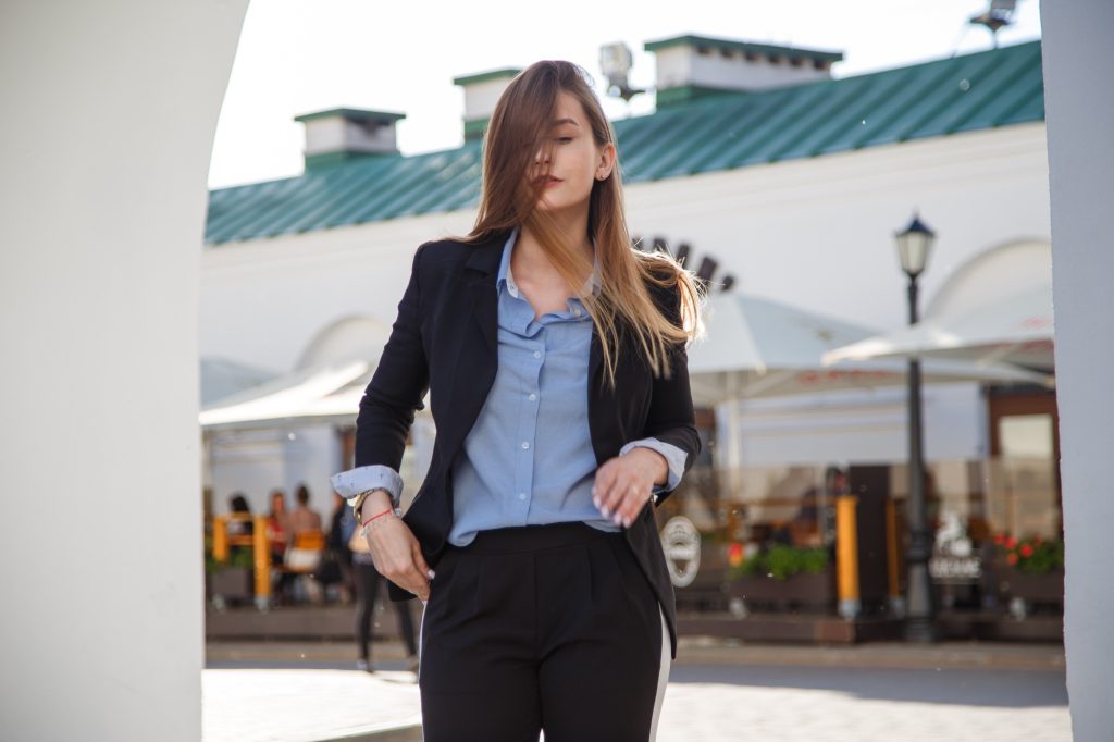 Fashionable women's look with black jacket and blue blouse.